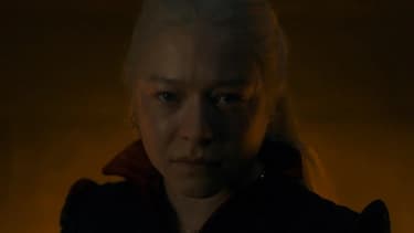 Closeup on Rhaenyra's face, backlit by a fireplace. Her expression shows pain and anger.