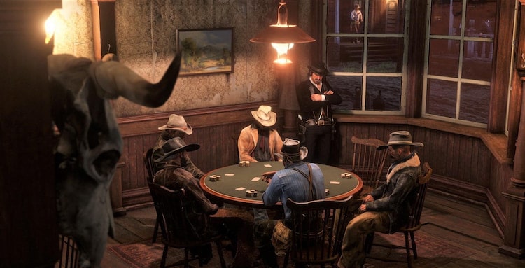 Cowboys sits around a table in a dimly lit saloon playing poker