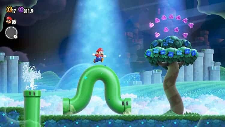 Mario is running on top of a green pipe with eyes. The pipe is bending in the middle with Mario on top. Another pipe is shooting water. A tree with purple collectibles is on the right. A spotlight is on Mario.