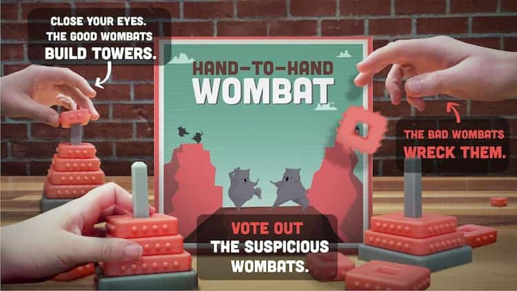 The Hand-to-Hand Wombat box is in the middle. Towers of varying stages of completion are set up near the box. Hands are picking up and placing the tower pieces. The text in the image explains the goal of the game.