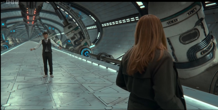 The Doctor and Donna stand in a very long CGI spaceship corridor