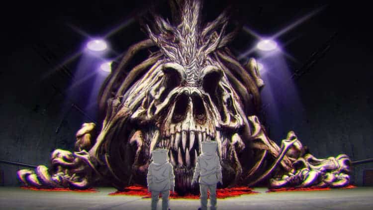 Two people in white protective gear and are standing in front of giant Godzilla bones. A red substance is underneath the bones. Four lights are illuminating the room they are in.