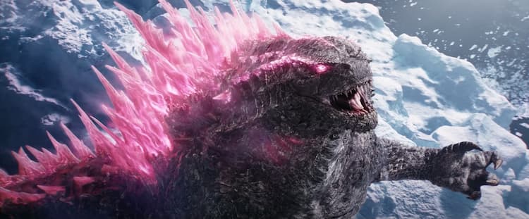 Godzilla is roaring and standing in a frozen environment. His dorsal fins and eyes are glowing bright pink. The ocean is surrounding where he is standing.