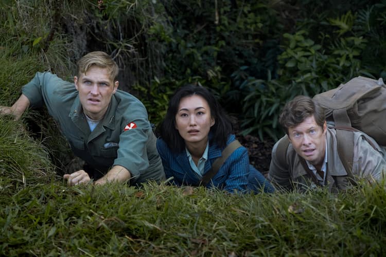 Shaw, Keiko, and Billy are lying down on the grass. They all have concerned/surprised loosk on their faces. The jungle can be seen behind them.