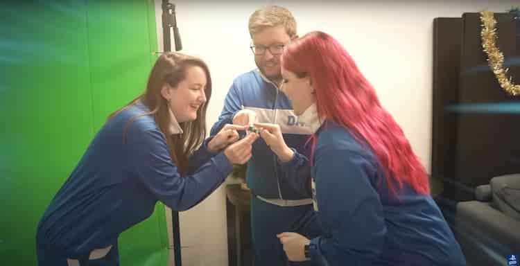 From left to right, Rosie, Dave and Ash touch a finger on a crystal bauble. A greenscreen can be seen on the left