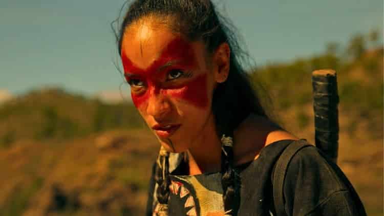 Native female warrior in native clothing with red face paint in the shape of a mask like Zorro. Preparing to fight