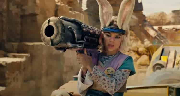 Tiny Tina is holding a rocket launcher while standing on a train. She has a look of contempt on her face. The train is moving through a mountainous area with a large rock wall in the background.