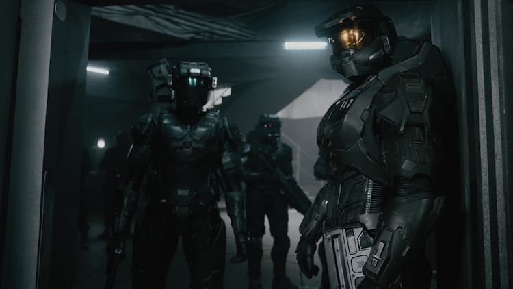 Chief, Kai, Vannak, and some soldiers are preparing to enter a room. The area is dark, and Chief and Kai don't have their weapons ready. Vannak is holding his gun in a ready position.