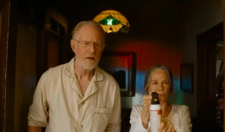 Ed Begley Jr, left, is looking towards the camera with a confused look on his face. Barbara Hershey, right, is holding a bear repellant spray can