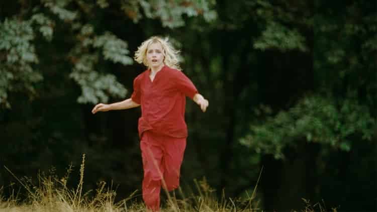 The Lady is wearing hospital scrubs and has blonde hair. She is running towards the camera.